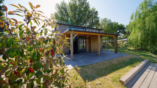 Lodge Tiny House Plus 4 sous le soleil, terrasse en bois, pelouse et arbres verdoyants tout autour