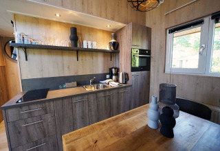 Moderne Küchenzeile mit Holzelementen und Esstisch im Tiny House Plus 4, Zuiderzee, Niederlande.