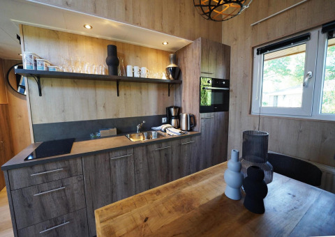 Moderne kitchenette met houten kasten en eettafel in Tiny House Plus 4, Zuiderzee, Nederland.