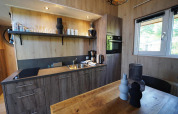 Moderne keukenhoek met houten kasten en tafel in Tiny House Plus 4, Zuiderzee, Nederland.