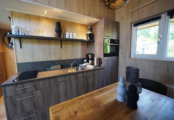 Moderne keukenhoek met houten kasten en tafel in Tiny House Plus 4, Zuiderzee, Nederland.