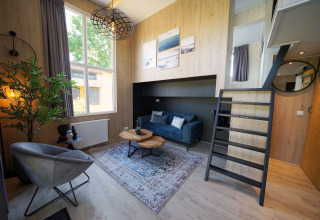 Modernes Tiny House Plus 4 bei Zuiderzee, Niederlande, mit stilvollem Wohnbereich und Hochbett.
