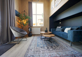 Soggiorno moderno al Tiny House Plus 4 a Zuiderzee, Paesi Bassi, con divano blu e dettagli eleganti.