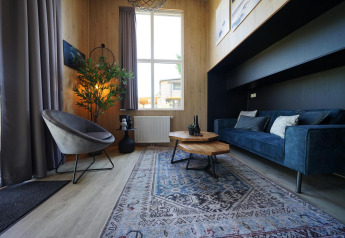 Moderne zithoek in Tiny House Plus 4 aan Zuiderzee, Nederland, met blauwe zetel en veel licht.