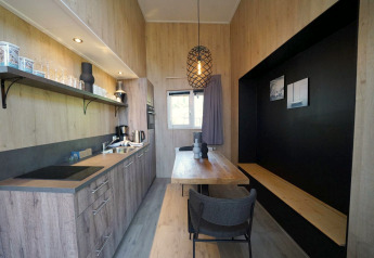Cucina e zona pranzo moderne e compatte al Tiny House Plus 4 a Zuiderzee, Paesi Bassi, interni in legno.