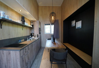 Moderne, compacte keuken en eetruimte in Tiny House Plus 4 bij Zuiderzee, Nederland, met houten interieur.