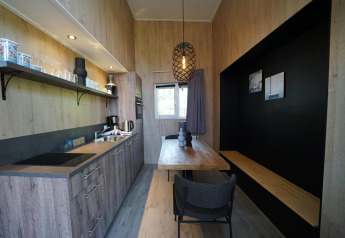 Moderne, compacte keuken en eetruimte in Tiny House Plus 4 in Zuiderzee, Nederland, met houten afwerking.