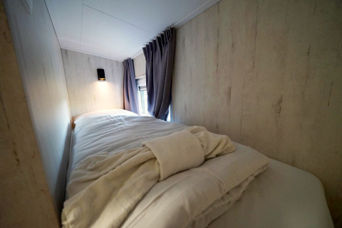 Gemütliches Schlafzimmer mit Bett und weichen Bettdecken im Tiny House Plus 4, Zuiderzee, Niederlande.