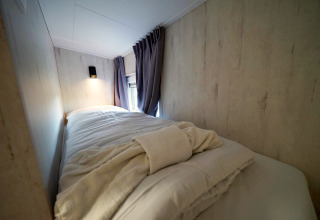 Gemütliches Schlafzimmer mit Bett und weichen Bettdecken im Tiny House Plus 4, Zuiderzee, Niederlande.