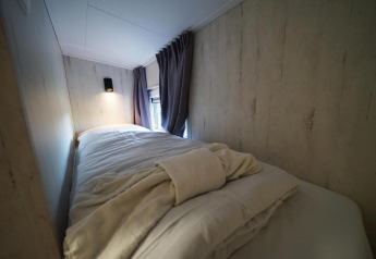 Gezellige eenpersoonskamer met zacht bedlinnen in Tiny House Plus 4, Zuiderzee in Nederland.