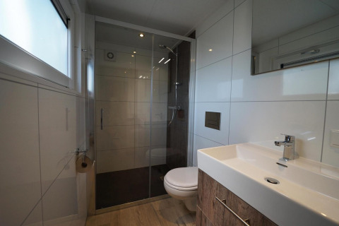 Moderne badkamer met inloopdouche en wandcloset in Tiny House Plus 4 bij Zuiderzee, Nederland.
