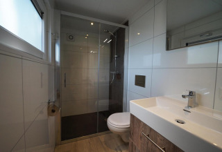 Moderne badkamer met inloopdouche en wandcloset in Tiny House Plus 4 bij Zuiderzee, Nederland.