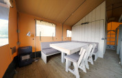 Indendørs udsigt af Glampingtent 6 ved Zuiderzee i Holland med moderne spiseområde og træmøbler.