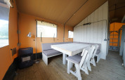 Indendørs udsigt af Glampingtent 6 ved Zuiderzee i Holland med moderne spiseområde og træmøbler.