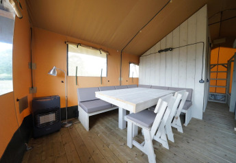 Interior view of Glampingtent 6 at Zuiderzee in the Netherlands featuring wooden floors and dining area.