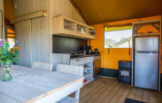 Modern glamping tent kitchen with wooden interior and dining table at Glampingtent 6, Zuiderzee, Netherlands.