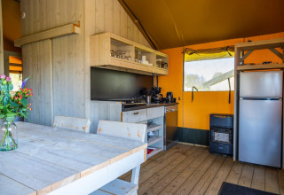 Cocina de tienda glamping moderna con interior de madera y mesa en Glampingtent 6, Zuiderzee, Países Bajos.