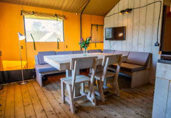 Innenraum von Glampingtent 6 im Zuiderzee, Niederlande mit Holztisch, Stühlen und Sofa.