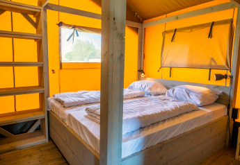 Intérieur de la Glampingtent 6 à Zuiderzee, Pays-Bas, avec lit double et éléments en bois.