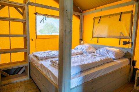 Interno di Glampingtent 6 a Zuiderzee, Paesi Bassi, con letto matrimoniale e dettagli in legno.