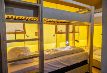 Lits superposés dans une tente glamping confortable à Zuiderzee, Pays-Bas, avec murs jaunes éclairés.