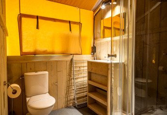 Modern bathroom with wooden decor, glass shower, toilet, and sink in Glampingtent 6 at Zuiderzee, Netherlands.