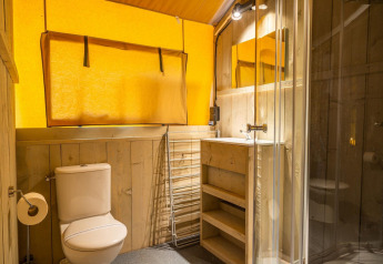 Modern bathroom with wooden decor, glass shower, toilet, and sink in Glampingtent 6 at Zuiderzee, Netherlands.
