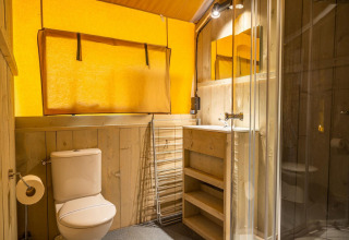 Bagno moderno con decorazioni in legno, doccia in vetro, WC e lavabo in Glampingtent 6 a Zuiderzee, Paesi Bassi.