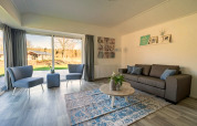 Salon lumineux et moderne du lodge Velthorst 4 à Zuiderzee, Pays-Bas, avec de grandes baies vitrées.