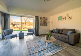 Bright, modern living room at Velthorst 4 lodge at Zuiderzee, Netherlands, featuring large windows and cozy seating.