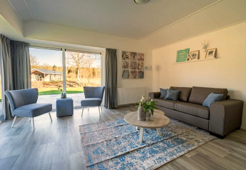 Soggiorno luminoso e moderno nel lodge Velthorst 4 a Zuiderzee, Paesi Bassi, con grandi finestre panoramiche.