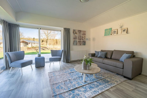 Soggiorno luminoso e moderno nel lodge Velthorst 4 a Zuiderzee, Paesi Bassi, con grandi finestre panoramiche.