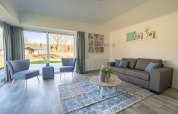 Lyst og moderne opholdsområde i Velthorst 4-lodgen ved Zuiderzee, Nederlandene, med store vinduer.
