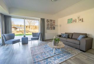 Soggiorno luminoso e moderno nel lodge Velthorst 4 a Zuiderzee, Paesi Bassi, con grandi finestre panoramiche.