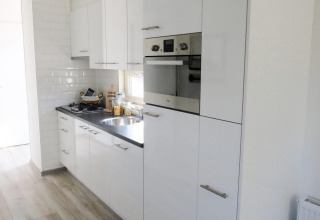 Moderna cucina bianca presso la lodge Velthorst 4 a Zuiderzee, Paesi Bassi, con forno integrato.