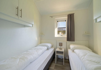 Slaapkamer met twee aparte bedden, tafeltje en venster in Velthorst 4 lodge bij Zuiderzee, Nederland.