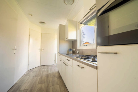 Modern kitchen area with white cabinets, gas stove, and window at Velthorst 4, Zuiderzee in the Netherlands.