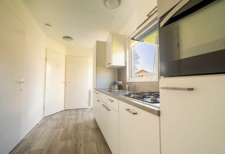 Modern kitchen area with white cabinets, gas stove, and window at Velthorst 4, Zuiderzee in the Netherlands.