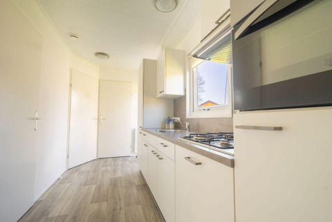 Moderne keuken met witte kasten, gaskookplaat en raam in Velthorst 4 bij Zuiderzee, Nederland.