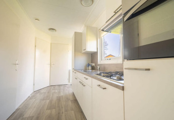 Moderne keuken met witte kasten, gaskookplaat en raam in Velthorst 4 bij Zuiderzee, Nederland.