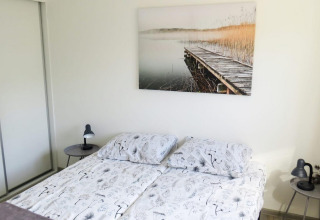 Camera da letto nella lodge Velthorst 4 a Zuiderzee, Paesi Bassi, con letto matrimoniale e tavolini.
