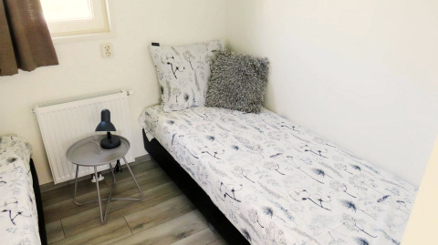 Room at Velthorst 4, Zuiderzee, Netherlands with single beds, bedside table, lamp and window.