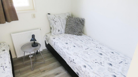 Slaapkamer in Velthorst 4, Zuiderzee, Nederland met eenpersoonsbed, nachtkastje en lamp.