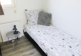 Slaapkamer in Velthorst 4, Zuiderzee, Nederland met eenpersoonsbed, nachtkastje en lamp.
