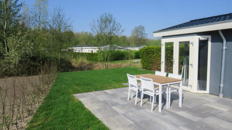Terras van lodge Velthorst 4 in Zuiderzee, Nederland, met zicht op tuin en tuinmeubilair.