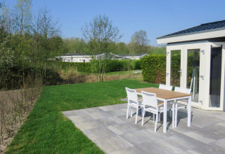 Terras van lodge Velthorst 4 in Zuiderzee, Nederland, met zicht op tuin en tuinmeubilair.