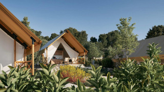 Sistemazione glamping con tende di lusso circondate da verde e alberi sotto un cielo limpido.