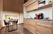 Modernes Glamping mit Küchenzeile in Holzoptik, Esstisch für vier und stilvollem Küchenzubehör.