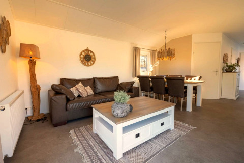 Wohnzimmer in einer Lodge mit braunem Sofa, Esstisch und naturinspirierten Deko-Elementen.