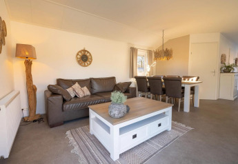 Lodge woonkamer met bruine zetel, witte salontafel, eethoek en natuurlijke decoratie met houtaccenten.